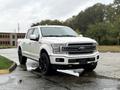 A white 2018 Ford F-150 with a glossy finish and black rims parked on a wet surface