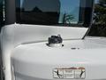 A white 2010 Bobcat E80 compact excavator featuring a circular fuel cap on the engine cover with a safety warning sticker attached