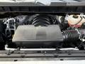 A close-up view of the engine compartment of a 2024 Chevrolet Silverado 1500 featuring the engine cover air intake and various components