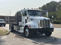 A 2020 Peterbilt 330 truck with a white body and black accents parked with its hood and grill prominently displayed