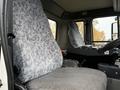 A gray patterned driver's seat inside a 2009 UD Trucks UD 3300 with controls and dashboard visible