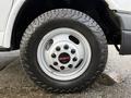 A close-up of a 2015 GMC Savana wheel featuring a white rim with a prominent black GMC logo and a rugged tire suitable for off-road use