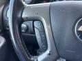 Close-up of a steering wheel in a 2011 Chevrolet Avalanche featuring control buttons for cruise control and a worn leather grip