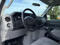 Interior view of a 2013 Ford Econoline showing the dashboard steering wheel and center console with control knobs and cup holders