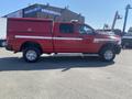 A red 2015 RAM 2500 truck with a white stripe and a matching truck bed cover parked on a lot