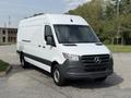 A white 2023 Mercedes-Benz Sprinter van with a black front grille and side mirrors is parked with its front angled toward the viewer