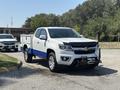 A 2017 Chevrolet Colorado pickup truck with a white body and blue accents parked with a front-mounted winch and a tool bed in the truck bed