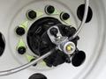 Close-up of a wheel hub assembly with a metal valve and braided hose attached to a black and green wheel rim on a 2011 Ford F-650
