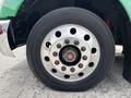A close-up view of a chrome wheel rim on a 2013 Kenworth T370 featuring multiple lug nut openings and a black tire with visible tread pattern