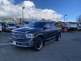 A 2017 RAM 1500 truck in dark gray color with a chrome grille and black wheels parked at a commercial lot