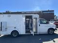 A 2013 Chevrolet Express ambulance with open side doors revealing the interior and seating area