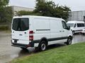 A white 2016 Mercedes-Benz Sprinter van with a high roof and rear doors parked on a wet surface