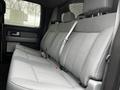 Interior view of a 2014 Ford F-150 showing the rear seats with a gray fabric upholstery and seatbelts