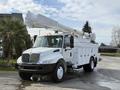 A white 2011 International 4300 bucket truck with an extended boom and utility storage compartments