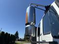 A chrome exhaust stack mounted on the side of a 2011 International 4300 truck reflecting sunlight