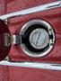 Close-up of the fuel filler cap on a 1970 Chevrolet Corvette showing a chrome opening with droplets of water on a red surface
