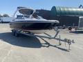 A 2013 Larson 238 boat on a trailer with a white and black exterior and a retractable bimini top