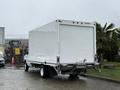 A white 2024 Ford E-450 box truck seen from the rear with a plain cargo area and visible tires on a wet surface