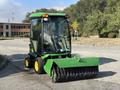 2021 John Deere 1575 with a green body and yellow wheels featuring a front-mounted broom attachment