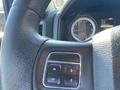 Close-up of a steering wheel with control buttons and a vehicle dashboard displaying information and a speedometer in a 2015 RAM 2500