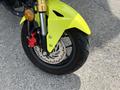 Close-up of a yellow 2018 Honda Grom front wheel showcasing the tire brake disc and caliper with a gold fork visible