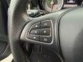 A close-up of a steering wheel control panel featuring buttons for navigation settings and information display on a 2016 Mercedes-Benz GLA-250