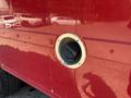 A close-up of a circular black vent with a brass trim installed on a red truck body