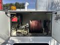A 2006 International 4300 truck with an open compartment showing a reel of red hose and various mechanical components including a pump and control panel