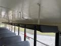 Interior view of a 2013 International 4300 school bus showing gray seats and overhead railing for securing belongings