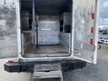 Interior view of a 2015 Ford F-550 with open rear doors showing aluminum shelving and storage compartments