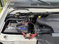 Under the hood of a 2002 Ford Econoline showing the battery and engine components with visible hoses and wires