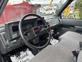 Interior view of a 2002 GMC C7500 truck featuring a black steering wheel with a red GMC logo and gray upholstery on the driver's seat