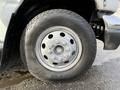 Close-up of a silver wheel of a 2002 Ford Econoline featuring a multi-spoke design and mounted on a rugged tire with visible tread patterns