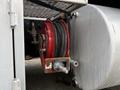 A red hose reel mounted on a silver tank with a coiled hose neatly wrapped around it