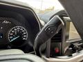 Close-up view of the steering wheel controls of a 2021 Ford F-150 featuring a gear shift lever with plus and minus buttons and a digital dashboard display