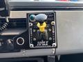 Control panel of a 1999 Freightliner FL80 featuring a gear shift lever with yellow knob and indicators for road and pump settings