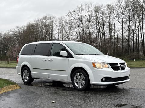 A white 2017 Dodge Grand Caravan parked with its front angled slightly towards the viewer showcasing its distinct grille and headlights