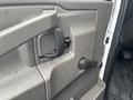 A close-up view of the interior door handle and lock mechanism of a 2018 Chevrolet Express with a textured gray panel and a crank handle for window control