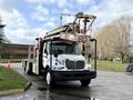 A white 2010 International 4300 truck equipped with a red and silver aerial ladder system mounted on its flatbed