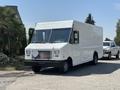 A 2012 Ford Econoline van with a white exterior and a boxy shape parked on a street