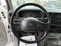 Steering wheel of a 2004 Ford F-750 with a Ford logo and various controls visible on the column and dashboard