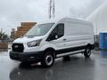 A 2022 Ford Transit van with a white exterior and black accents parked on a wet surface