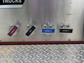A close-up of four control valves labeled Intake 2, Drain, Discharge 3, and Discharge 4 on the side of a 2002 GMC C7500 truck