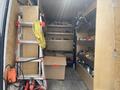 A 2022 Mercedes-Benz Sprinter van with wooden shelves filled with tools and equipment a ladder and a cardboard box are also present inside
