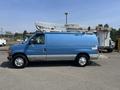 A blue 2005 Ford Econoline van with a utility bucket attachment on top parked on a gravel surface
