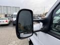 Close-up of the side mirror of a 2022 Ford E-450 showing water droplets on the glass with a black housing and two mounting arms