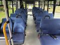 The interior of a 2020 Chevrolet Express featuring blue seats arranged in a row with seatbelts and a spacious aisle in the center