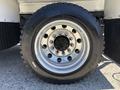 Close-up of a shiny chrome wheel rim with multiple holes and a mounted black tire featuring deep treads on a large vehicle