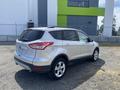 A silver 2015 Ford Escape is parked at an angle showcasing its sleek design and alloy wheels with a view of its rear and side
