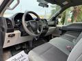 Interior of a 2018 Ford F-150 with gray cloth seats a steering wheel and dashboard showing controls and a gear shift